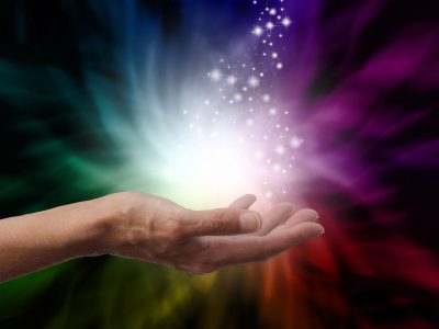 Healer's hand outstretched into magical healing energy field with a dusting of sparkles